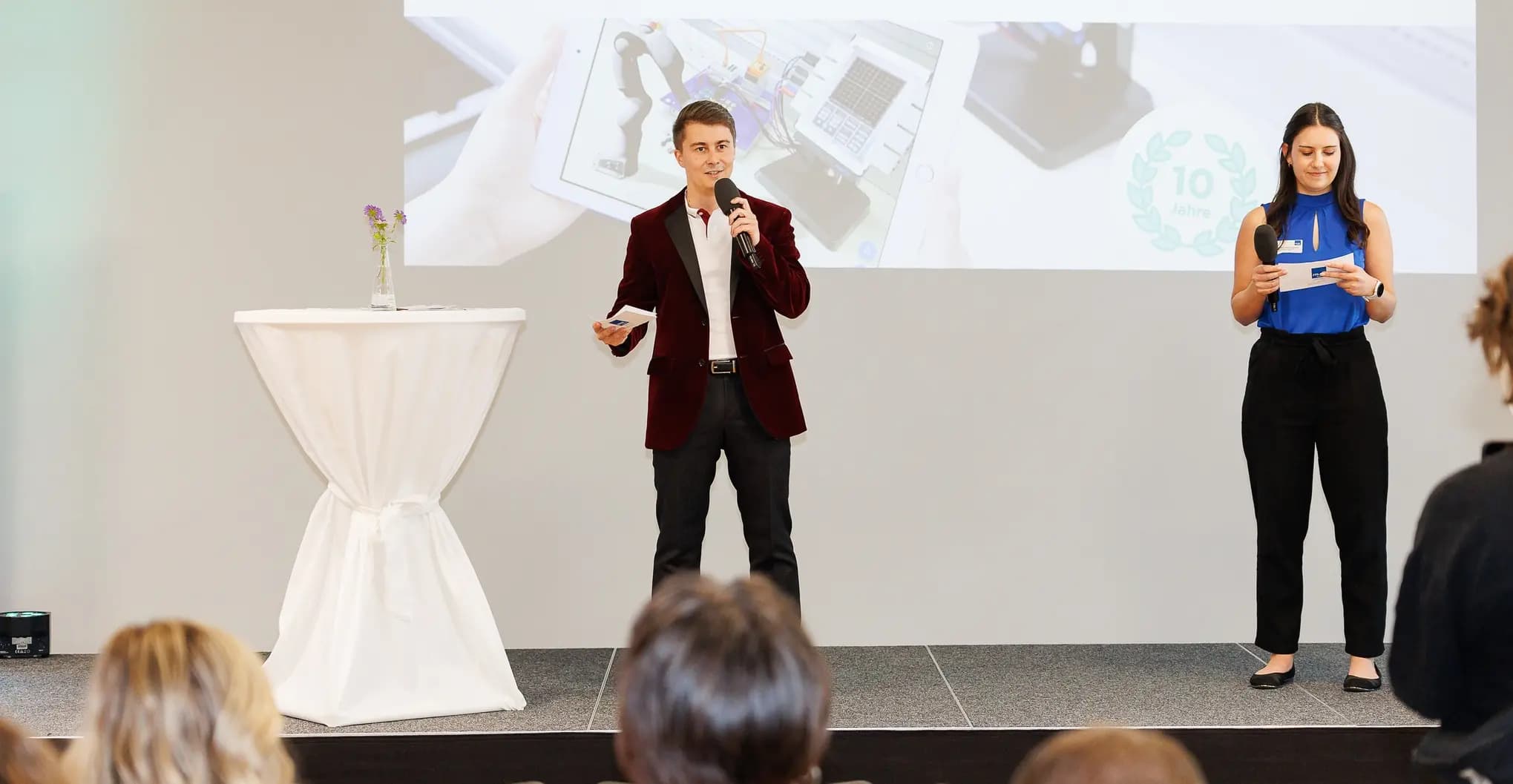 Michael Macher moderiert eine Veranstaltung — am Mikrofon vor Publikum.